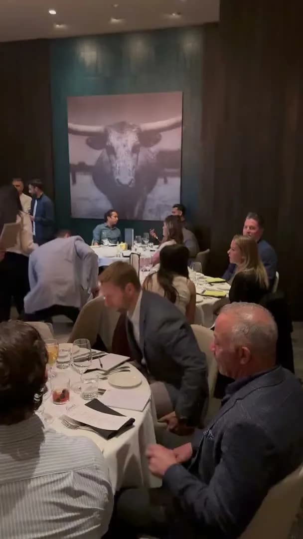 Guests seated at round tables beneath a large longhorn photograph
