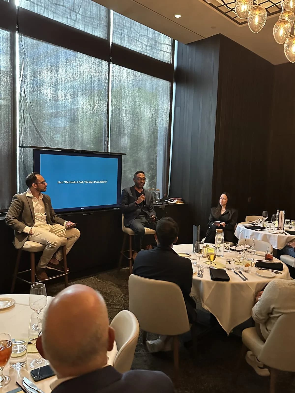 The talk seen across the tables, both speakers framed by the windows