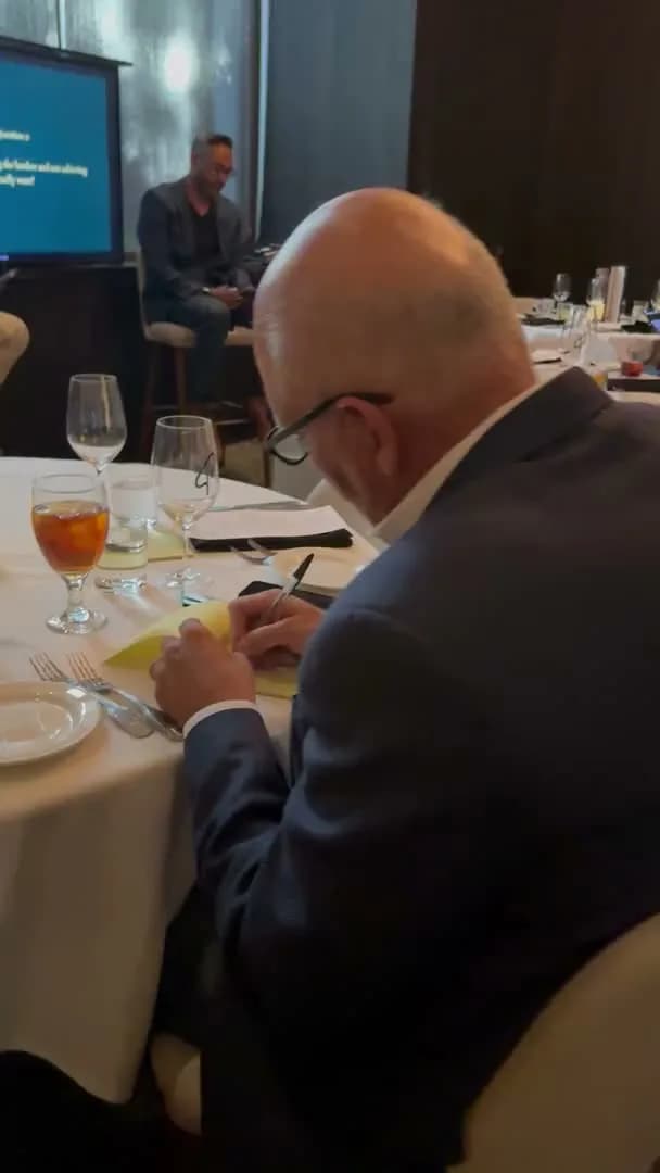 A guest writing notes on a card while the speaker talks