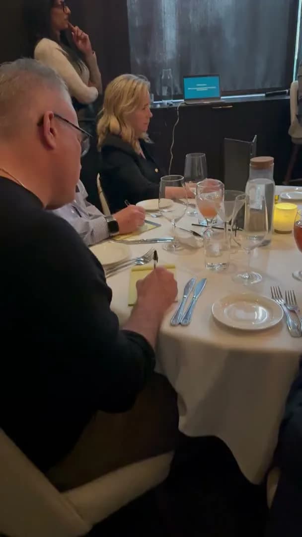 Two guests taking notes while the presentation runs from a laptop at the front