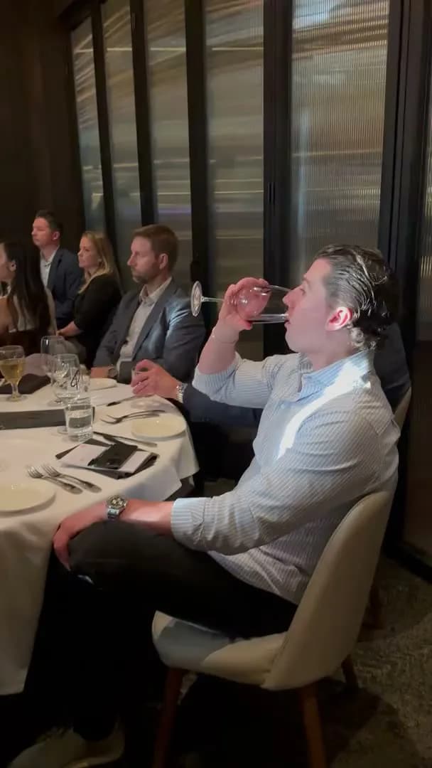 A guest raising a glass while listening