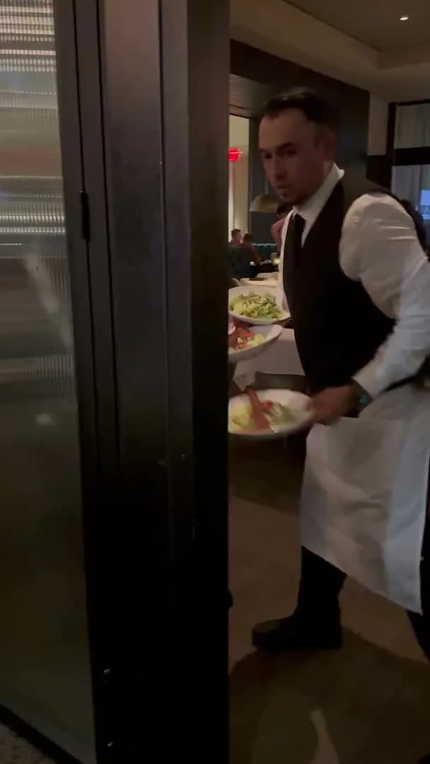 A server bringing the salad course from the kitchen